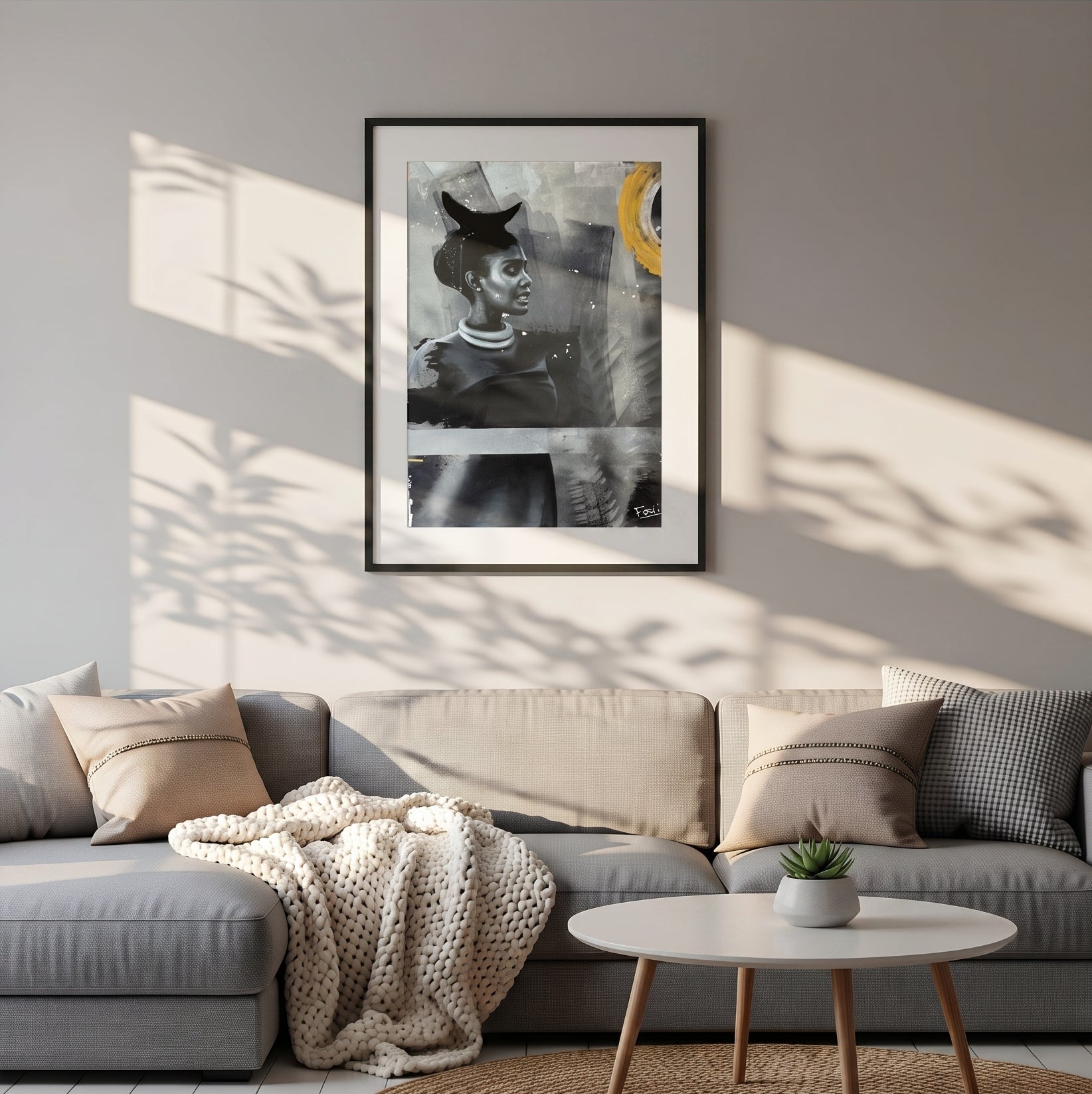 My footprints by feli the artist is A framed art print featuring an abstract portrait of a woman in black, gray, and white with a bold yellow circular accent, presented in a black frame with a white mat hang on a livingroom wall above a grey sofa with shadows on the wall.
