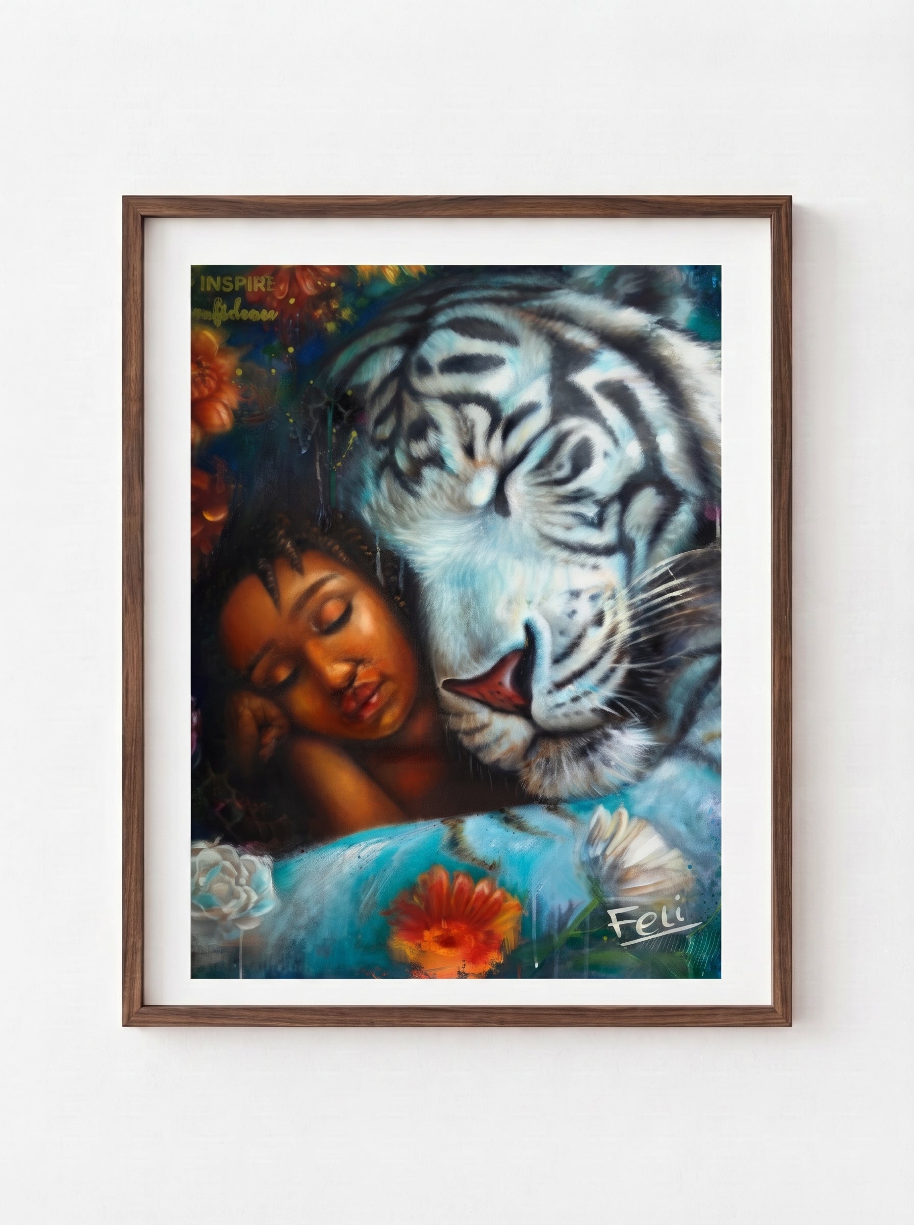 A framed art print entitled wild heart gentle soul by feli the artist featuring a painted scene of a sleeping woman resting against a large white tiger, with flowers and a dark blue background, shown hanging in a dark wood picture frame on a light wall.