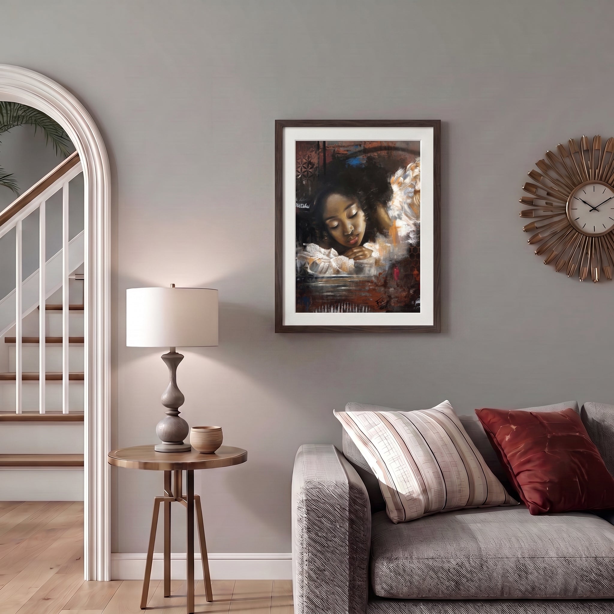 A framed art print entitled reflections by feli the artist featuring a portrait of a black african girl woman in a dark, moody setting, displayed in a dark wood frame on a gray wall in a styled living room next to a side table with a lamp and a gray sofa.


