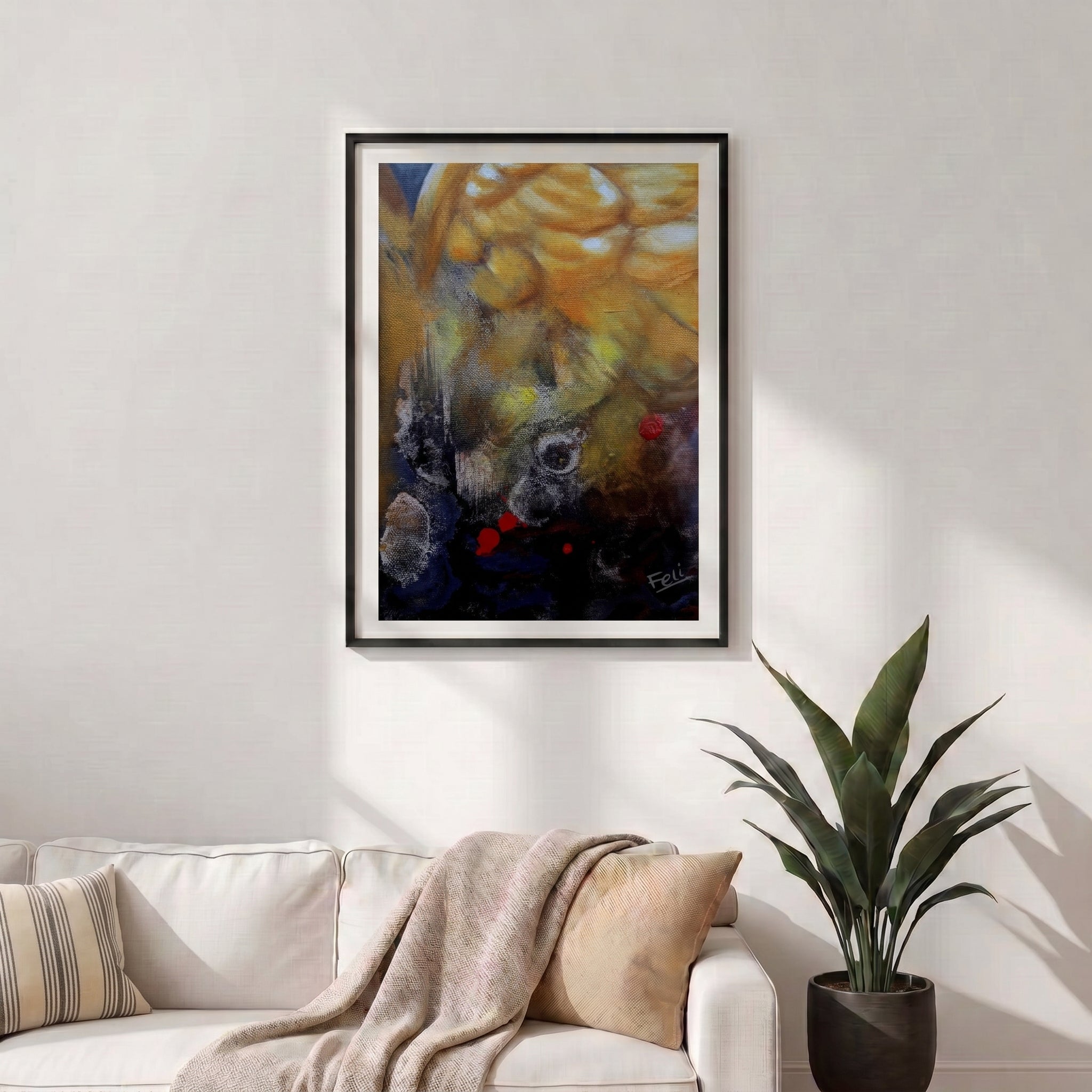 A framed abstract art print entitled my wings by feli the artist featuring a golden-yellow and dark blue design with small red accents, displayed in black frame on a white wall above a modern white sofa with a beige throw blanket and a potted green plant.