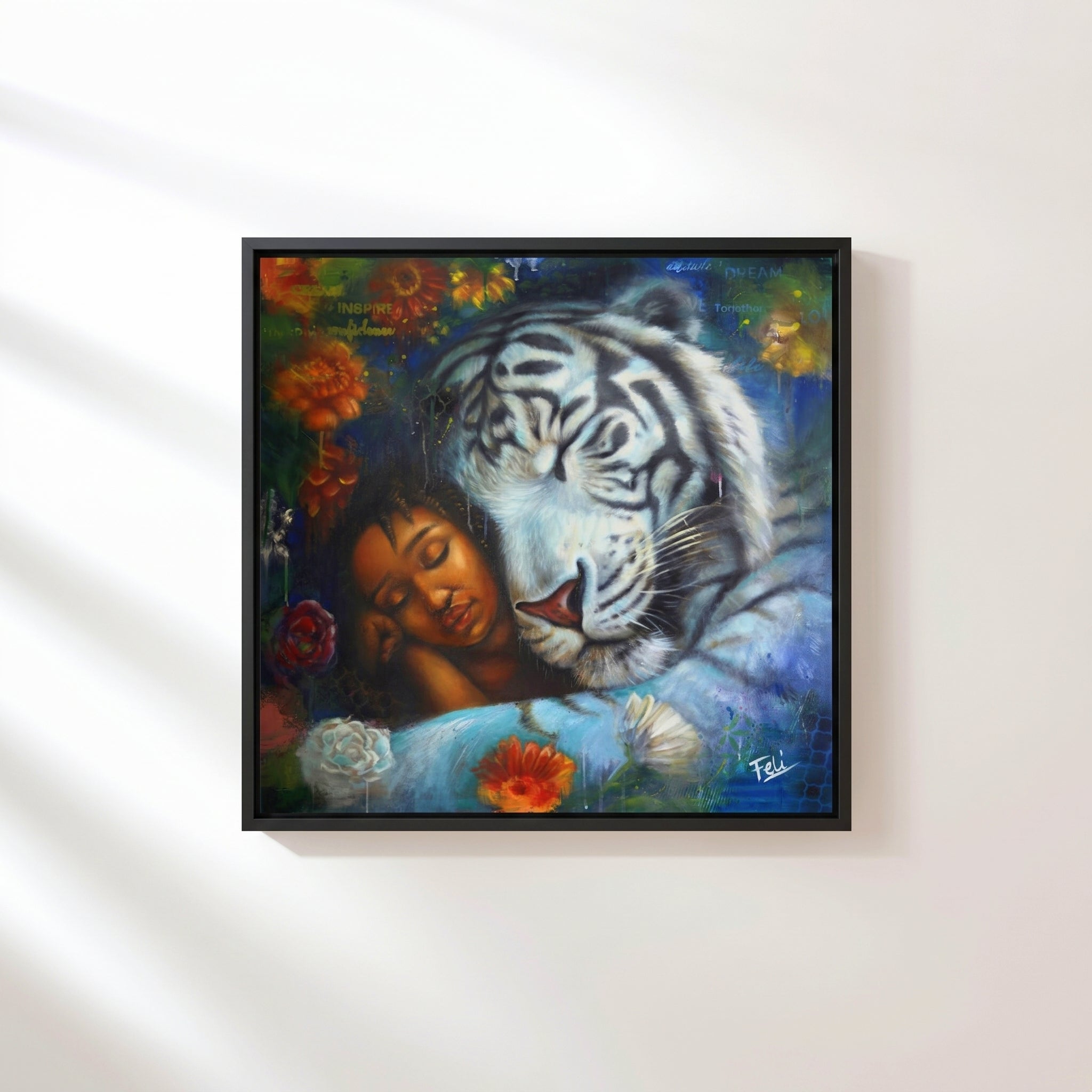 Wild heart gentle soul by feli the artist A framed art print hang on a white wall showing a sleeping woman resting her head against a large white tiger, surrounded by colorful flowers and dark blue background tones.

